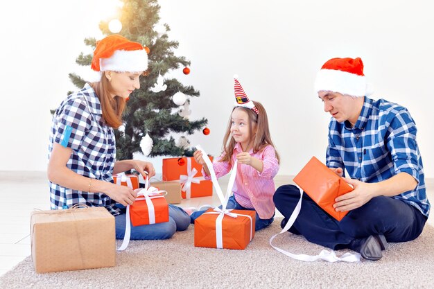Concetto di vacanze e regali - ritratto di una famiglia felice che apre i regali nel periodo natalizio.