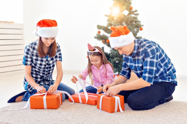 休日とプレゼントのコンセプト-クリスマスの時期に贈り物を開く幸せな家族の肖像画。