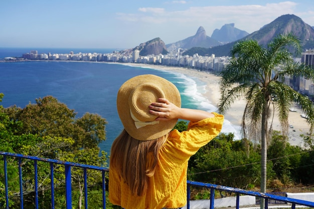 Photo holidays in rio de janeiro back view of tourist girl enjoying view of copacabana beach from viewpoint in rio de janeiro brazil