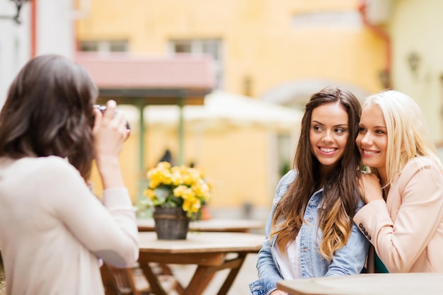 holidays and tourism concept - beautiful girls taking picture in cafe in city