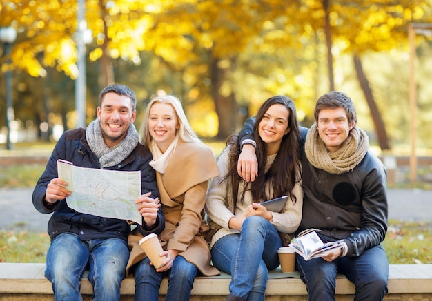 Vacanze e concetto di turismo - gruppo di amici o coppie con mappa turistica nel parco autunnale