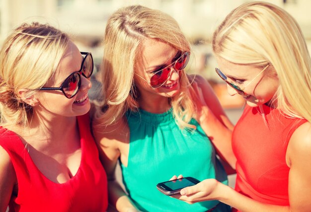 отдых и туризм, современная технологическая концепция - красивые блондинки со смартфоном в городе
