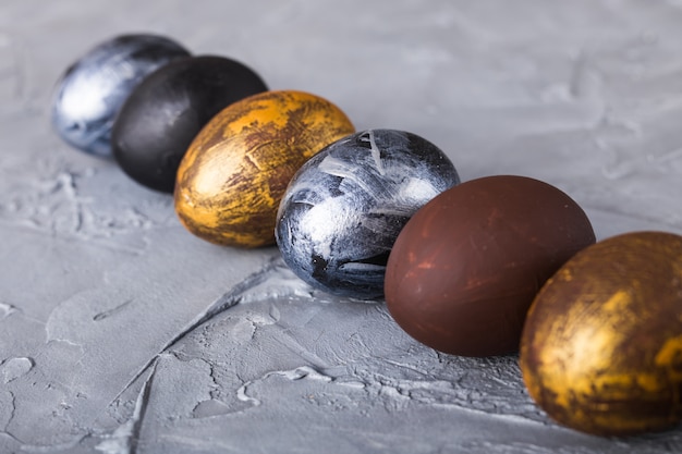 Праздники, традиции и концепция Пасхи - темные стильные пасхальные яйца на сером фоне.