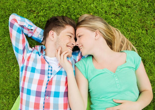 holidays, vacation, love and friendship concept - smiling couple lying on blanket in park