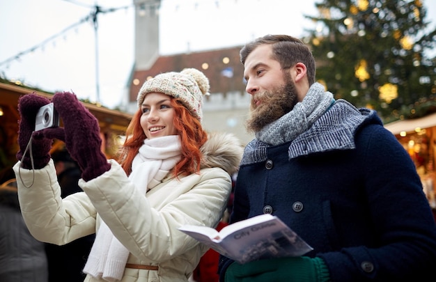 휴일, 겨울, 크리스마스, 기술 및 사람 개념 - 구시가지에서 스마트폰으로 사진을 찍는 따뜻한 옷을 입은 행복한 관광객 커플