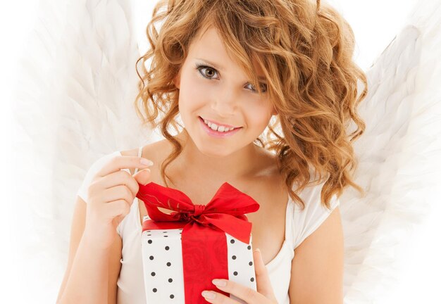 holidays, xmas and costumes concept - happy teenage angel girl with christmas gift