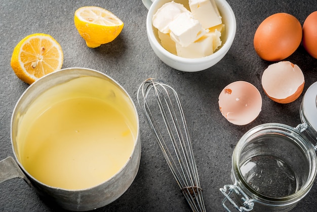 Hollandaise sauce in a metal saucepan, with ingredients for the recipe