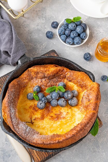 Hollandse baby pannenkoek met verse bosbessen munt en bestrooid met poedersuiker in ijzeren koekenpan