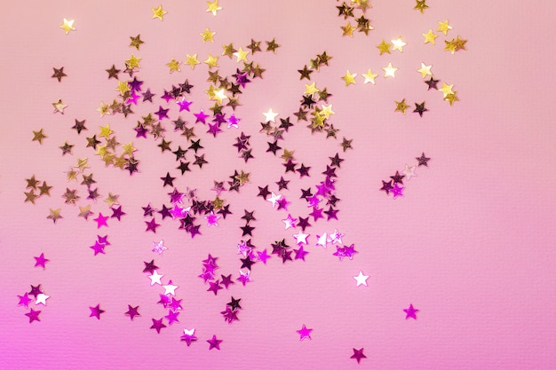 Holographic confetti stars on pink neon background.