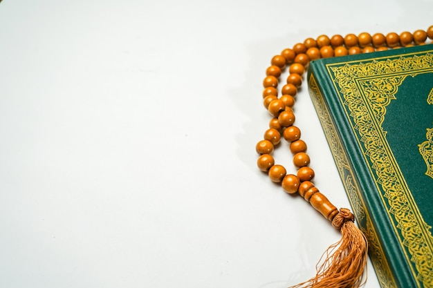 The Holy Al Quran with written arabic calligraphy rosary beads or tasbih on white background