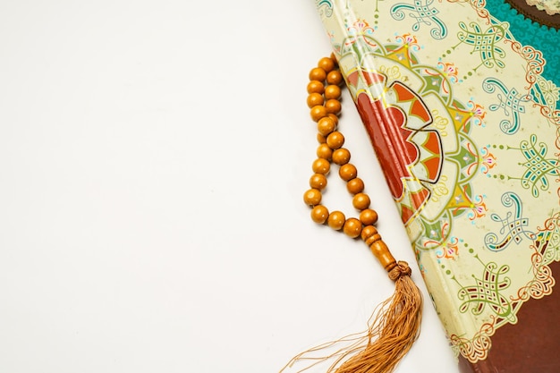The Holy Al Quran with written arabic calligraphy rosary beads or tasbih on white background