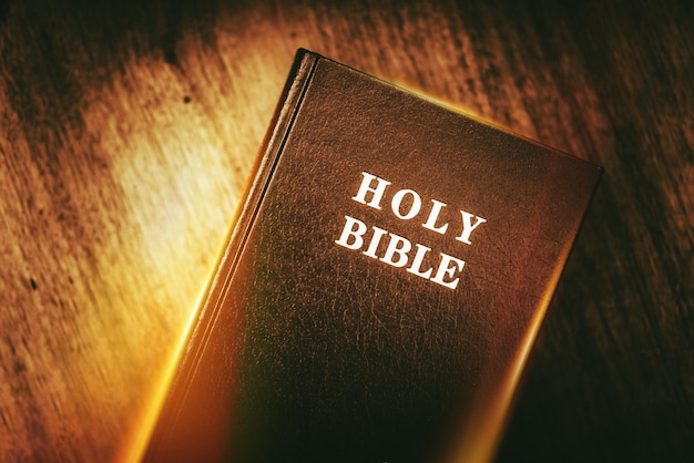 Photo holy bible in dark browny vintage color grading glowing light holy bible