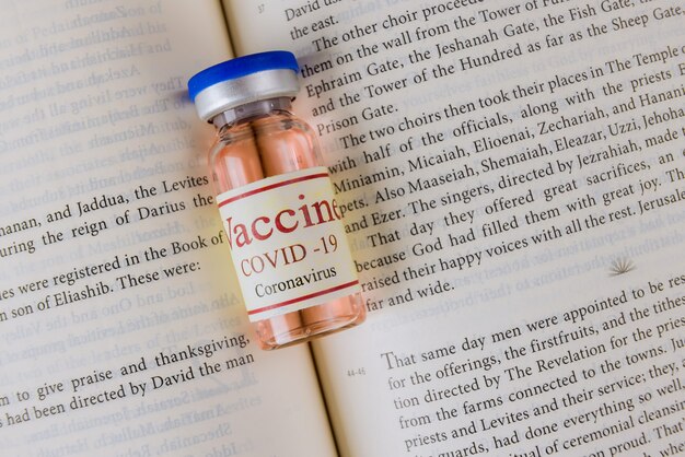 Holy Bible readings and prayer and covid-19 vaccine bottle, the attitude of the church to vaccination