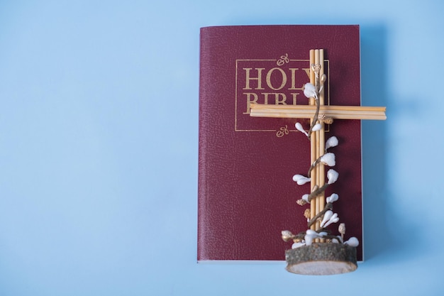 Holy Bible with cross and decorative flowers on blue background