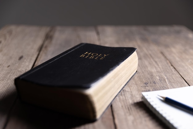 Photo holy bible on the wooden table holy bible with note book and pencil on wooden table against morning sun light for christian devotion copy space