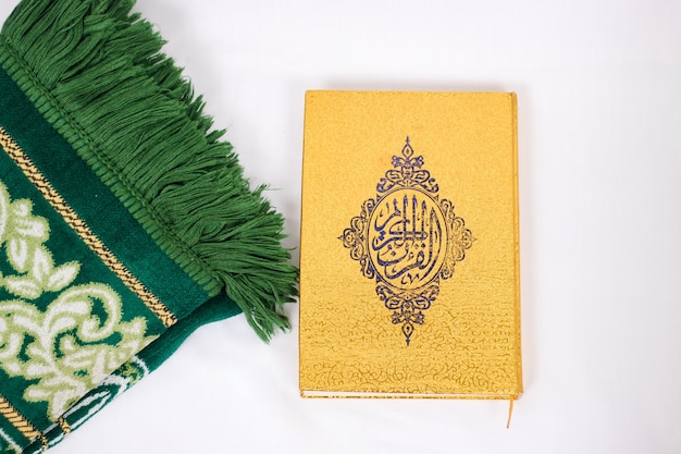 The holy book al quran and prayer rug isolated on white background