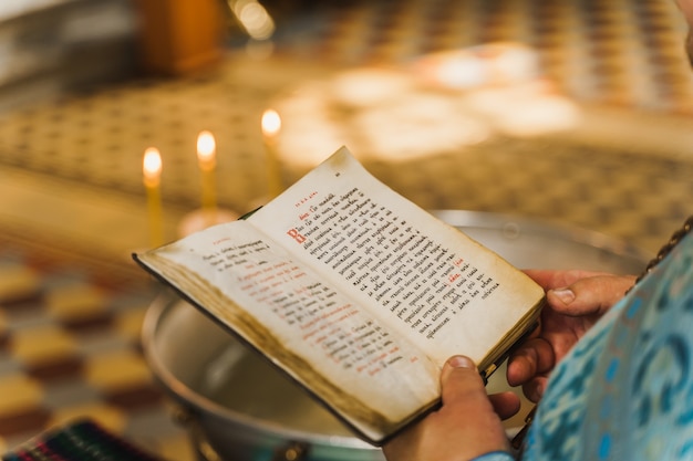 Holy book opened in priest hands in church