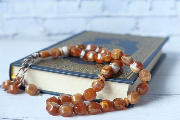 Holy book quran and rosary on table close up