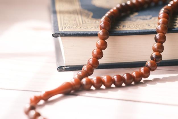 Photo holy book quran and rosary on table close up