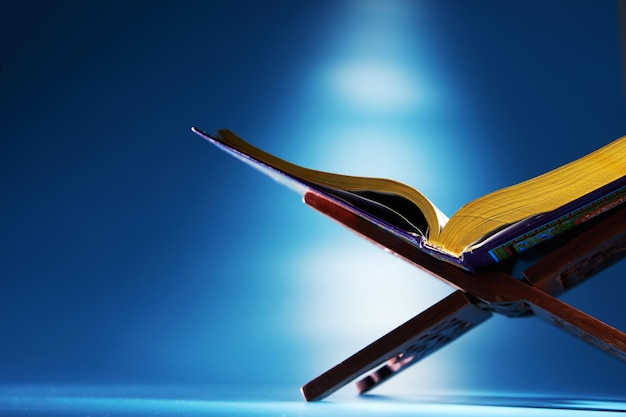 Holy koran on wooden stand against blue background