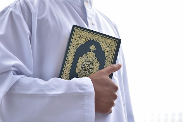 Holy Quran in hand with arabic calligraphy meaning of Al Quran