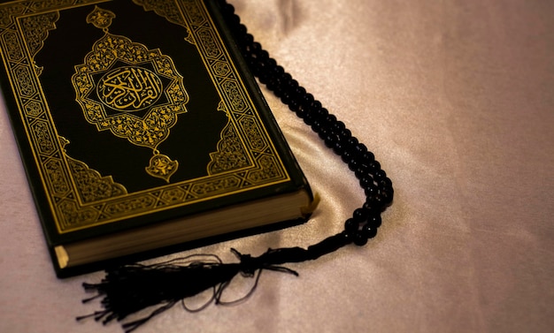 Foto il santo corano su una stuoia con perline nere di preghiera tasbih nero con oroun concetto islamico