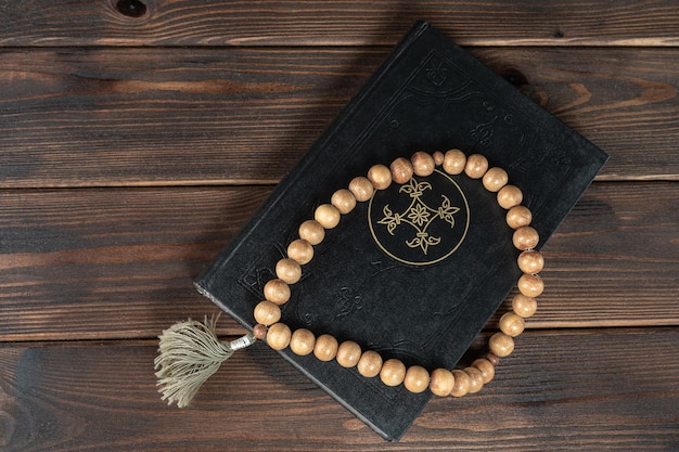 Holy Quran with beads on wooden background