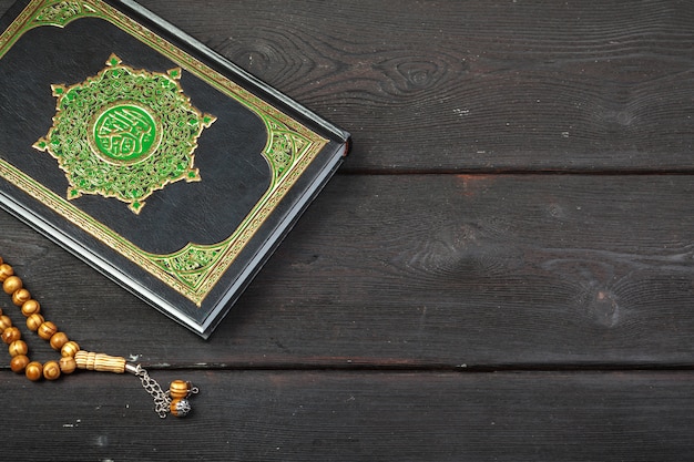 Holy Quran with beads over wooden surface