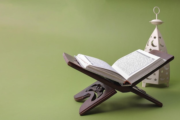 holy quran with lantern on green sage background