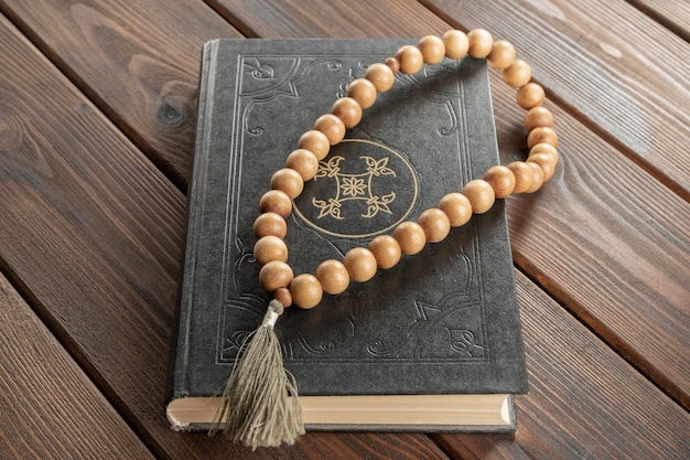 The Holy Quran with rosary beads on wood background. Islamic and Ramadan concept.