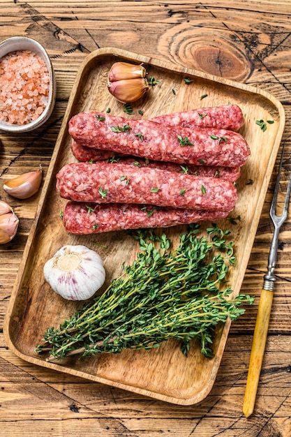 Homamade raw mince meat  sausages on a cutting board. wooden background. Top view.