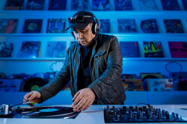 Hombre Dj mezclando musica en un tornamesa con discos de vinil y escuchando en los audifonos