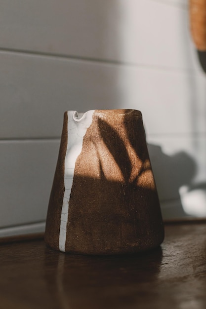 Home aesthetics Modern ceramic kettle in sunlight on rustic wooden chair and leaves shadow