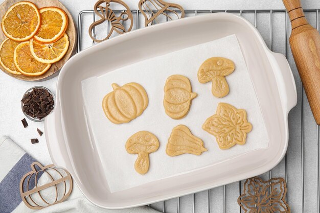 Photo home baking flat lay composition with uncooked biscuits of different shapes and cookie cutters on light table