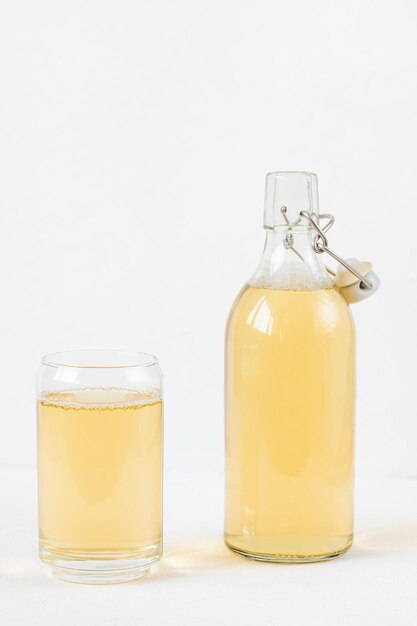 Photo home brewed kombucha fermented drink in glass and bottle on white heathy homemade beverage