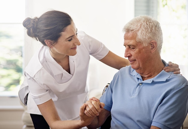 Home care with compassion Shot of a caregiver helping a senior man in a wheelchair at home