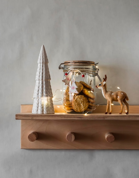 Home Christmas decor Ceramic Christmas tree cookie jar and lighted garland on a wooden shelf on the wall