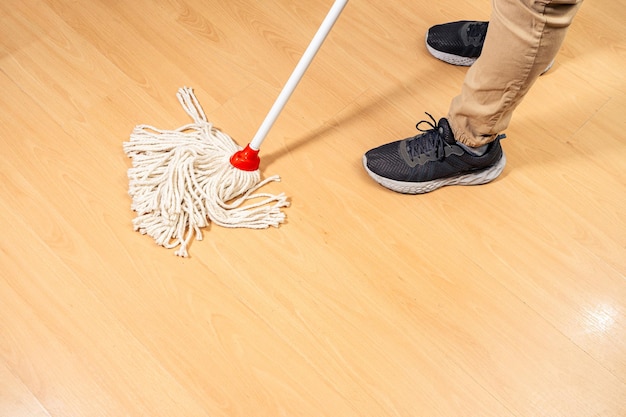 Detergente per la casa, uomo che pulisce i pavimenti in legno con una scopa in corda. concetto di lavoro domestico.