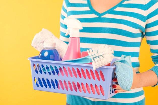 Home cleaning products. Housekeeping concept. Woman holding basket with basic supplies set.