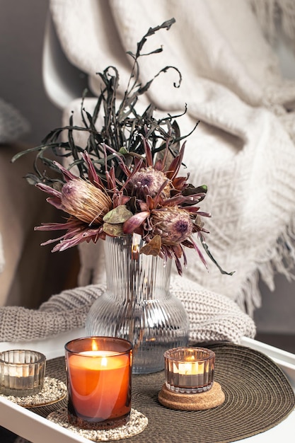 Home composition with a bouquet of protea flowers and candles