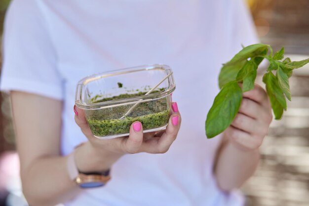 Home cooking  pesto sauce and green basil in the hands of young woman with a beautiful manicure Natural healthy eating Organic food High quality photo