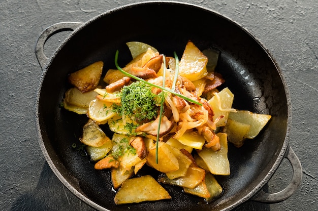 Home cooking. Potato fried in pan garnished with herbs and spices.