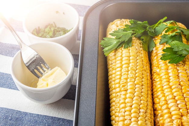 Ricetta casalinga mais al forno con sale, burro e coriandolo o prezzemolo al cartoccio. concetto di cibo fatto in casa. mangiare sano vegetariano.