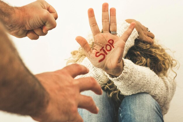 Photo home couple violence abuse concept with woman protect herself sitting on the floor and stop on the hand and man ready to beat up and assault her domestic crime problem issue for people