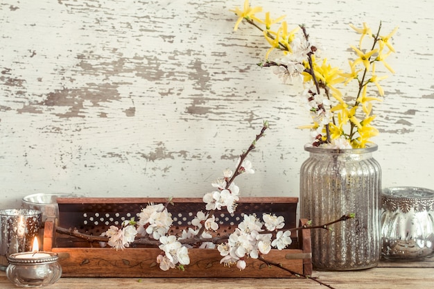 家の居心地の良い美しい装飾、さまざまな花瓶、木製の背景、インテリアの詳細の概念の春の花とキャンドル