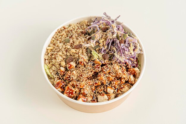 Home delivery container with bowl of chicken vegetables sunflower seeds raisins white and red quinoa purple kale pumpkin seeds sesame seeds and yakitori sauce