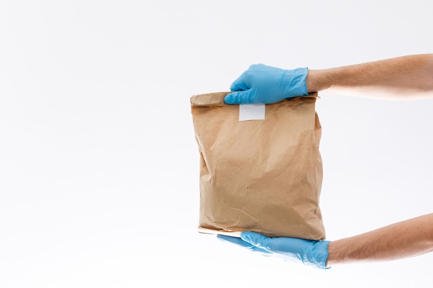 home delivery, online order. A man in uniform, a medical mask and rubber gloves with a box, a parcel in his hands. Food and food delivery during the quarantine of the coronavirus pandemic