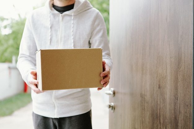 Photo home delivery shopping box man wearing gloves and protective mask delivering packages at door.