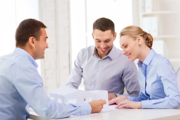 home, design and architecture concept - couple looking at blueprint and model of their new house at office