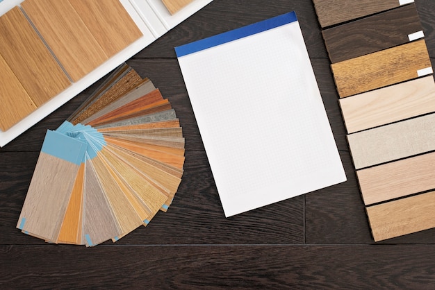 Photo home design concept with a sample of natural wood material for customers. laminate and vinyl floor design palette and blank notebook for drawings. construction and repair.